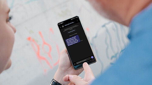 Jemand liest eine WhatsApp-Nachricht auf seinem Smartphone: „Hallo Papa, ich habe eine neue Nummer. Könntest du mir die auf die Taschenschau schicken? WhatsApp-App schreiben?“