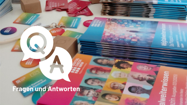 „Fragen und Antworten“ mit Werbematerialien und Ansteckern auf einem Tisch